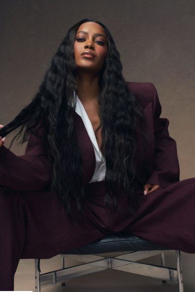 Ciara Miller poses in a burgundy suit. Her hair is styled in waves.